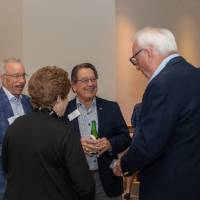 Jim Brooks standing in circle and chatting with three event attendees
